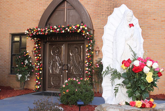 The setting sun illuminates the statue of Our Lady of Guadalupe and the Holy Door at Our Lady of the Americas Mission, Lilburn. Thirty-two-year-old Jose Morales made the door especially for the Holy Year of Mercy. Photo By Michael Alexander