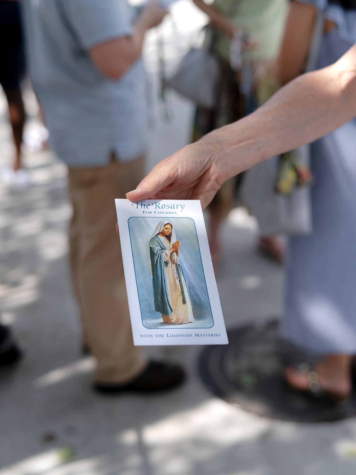 Legion of Mary member Cathy Longtin holds out one of the pamphlets being distributed at a recent outreach event. Photo by Johnathon Kelso