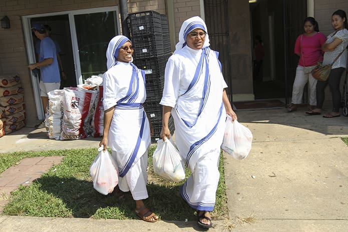 Missionaries of Charity Sister Leo Grace, left, and superior Sister Justus take chicken from their Clarkston apartment to a volunteer’s vehicle where the chickens, along with other food, were taken to the Colony South mobile home park in southeast Atlanta Aug. 27. After a time of prayer, food was also distributed to families from their Clarkston apartment on the same day. Photo By Michael Alexander