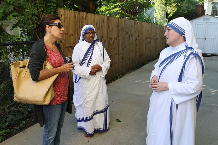 Standing in the driveway at the Gift of Grace House, Maria da Silva, left, a Cathedral of Christ the King parishioner and a volunteer for 11 years, talks with Missionaries of Charity Sister Dominga, right, as Sister Maxmilina, center, looks on. Photo By Michael Alexander