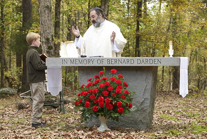 Father Stephen Lyness, pastor of Queen of Angels Church, Thomson, and St. Joseph Church, Washington, conducts the opening prayer during the Nov. 8 Mass at the Locust Grove Cemetery. Holding the prayer book for Father Lyness is 11-year-old Grant Pixley of Macon, the great-grandchild of the late Bernard R. Darden, the name inscribed on the altar. Dardenâs widow had the altar erected and donated to the cemetery, although he was buried at the Purification Cemetery when he died in 1986. Photo By Michael Alexander