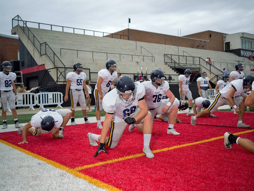 Marist defensive lineman Roscoe Hutchinson, center, stretches before the game against Woodward Academy on Sept. 9. Photo by Johnathon Kelso