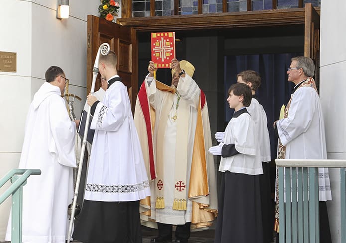 After opening the Holy Door of Mercy at the Monastery of the Holy Spirit, Conyers, Archbishop Wilton D. Gregory holds the Book of the Gospels over his head for the congregation to see before entering the Holy Door. Photo by Michael Alexander