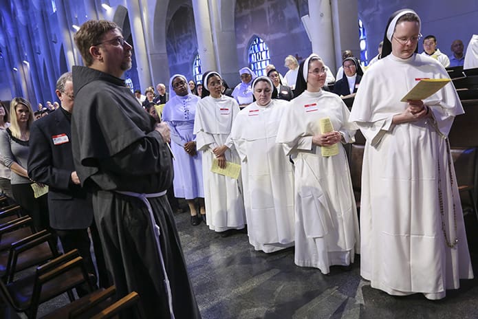 Conventual Franciscan Father Gary Johnson, foreground left, a parochial vicar at Holy Cross Church, and Dominican Sisters from St. Catherine of Siena School, Kennesaw, foreground right in white habits, join a host of other consecrated religious in praying during the evening liturgy of praise, the Divine Office of Vespers. Photo by Michael Alexander