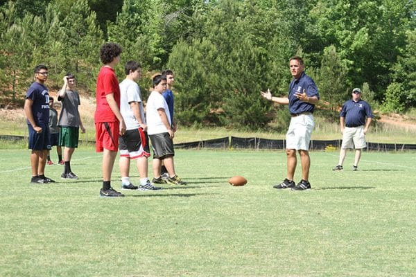 As the team runs through a practice without uniforms, helmets and pads, head coach Kurt Page, second from right, provides instructions to the defensive players. Looking on is assistant coach Matt Daniels, far right. Photo By Michael Alexander