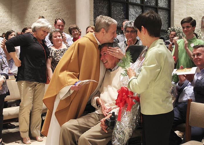 Msgr. Patrick Bishop embraces his childhood friend Stephen Boothe as Boothe’s wife, Melinda, looks on. During his May 17 retirement Mass, Msgr. Bishop renewed the wedding vows of the couple from St. Thomas the Apostle Church, Smyrna. Like the monsignor who is celebrating his 40th anniversary as priest, the couple is also celebrating 40 years of marriage. Photo By Michael Alexander