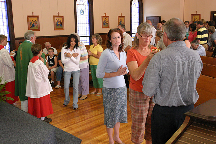 Anthony Emanuel, far right, extraordinary minister of the Eucharist and parish council president, extends the blood of Christ to Lynn Leinberger. Waiting behind Leinberger is Regina Gilley, who in addition to helps open the church and make preparations for Mass, also has coordinated the food for the potluck for the last year. Photo By Michael Alexander