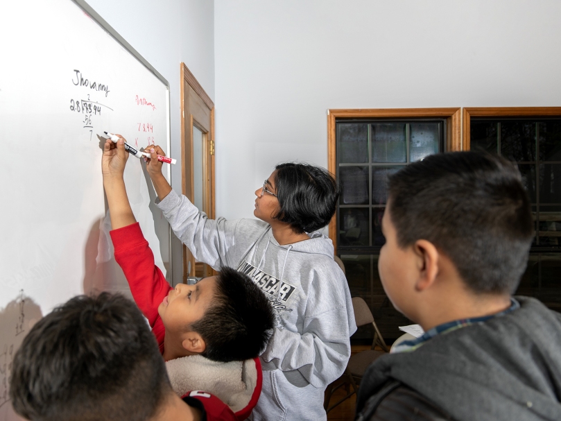 Tuto Srujana Sivakumar helps students with math during an after-school program at Cumming's St. Brendan the Navigator. It's a program that the organizer thinks other parishes could easily replicate. Photo by Johnathon Kelso