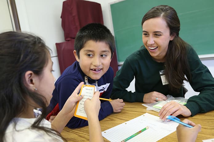 Brittany Anderson, right, conducts an exercise about U.S. states and capitols with second-graders Jesus Salina, center, and Abril Osorio. Anderson, a University of Georgia graduate student pursuing a masterâs degree in education, started tutoring at the beginning of the 2014 spring semester. Photo By Michael Alexander