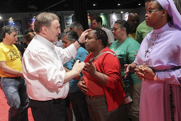 During the healing service that followed the opening Mass of the Eucharistic Congress, Alan Ames lays hands upon Kenide Celestin of St. John Vianney Church in Lithia Springs. Photo By Michael Alexander