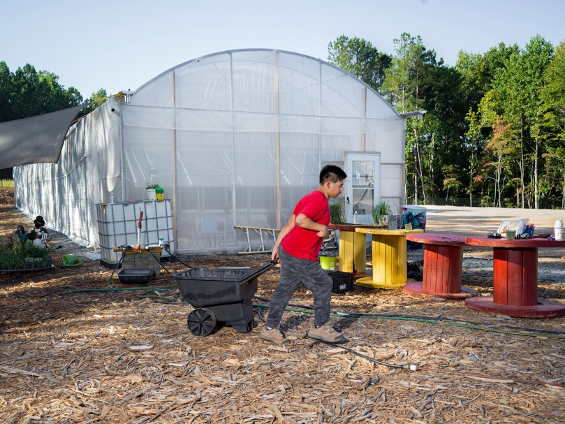 Joseph Newton hauls mulch to a garden bed during a day of work at Peachtree Farm, an equitable employment farm for adults with disabilities. The farm was started by a St. Jude the Apostle Church parishioner. Photo by Johnathon Kelso