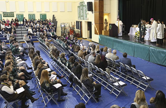 Seniors Molly Dankowski and Jeffery John present Pinecrest Academy Paladin gifts to Bishop Bernard E. Shlesinger III as other students and guests look on. Bishop Shlesinger was the main celebrant and homilist during the Feb. 2 Founder’s Day Mass at the Cumming school. Photo By Michael Alexander