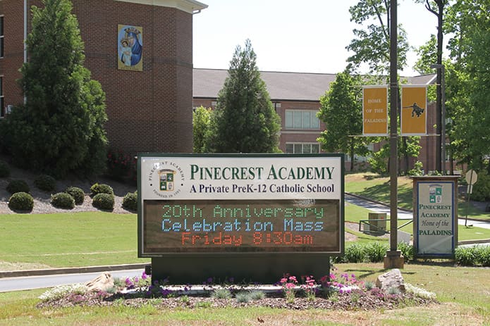 A sign at the schoolâs entrance announces the 20th anniversary Mass at Pinecrest Academy, Cumming. Photo By Michael Alexander