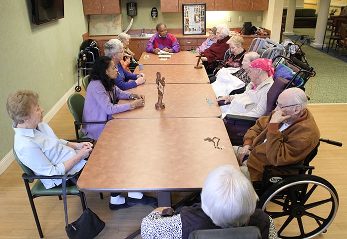 The residents join David Waters, top end of the table, and his wife Mary, bottom end, second from left, around the table as they pray the rosary. The skilled nursing residents sit on the right side, while the independent living and personal care residents sit on the left side. Photo By Michael Alexander