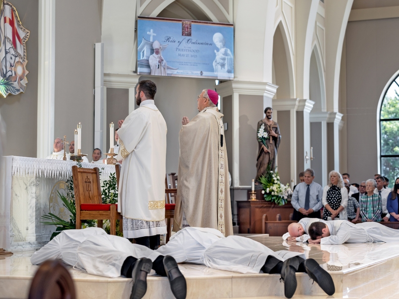 Candidates lay prostrate near the altar during the ordination to the priesthood as Archbishop Gregory J. Hartmayer, OFM Conv., and the faithful pray with them. Photo by Johnathon Kelso