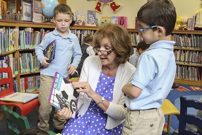 Immaculate Heart of Mary School librarian Sandy Wilson has always had the desire to help instill a love for reading in children. Here she helps kindergarten students Tommy Hodan, left, and Manuel Villalon look for the books they wish to check out of the school library. Wilson is retiring at the end of the current school year after 38 years at the Atlanta school. Photo By Michael Alexander