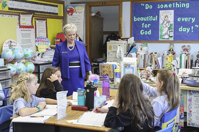 St. Thomas More School fourth-graders (clockwise, from bottom left) Abigail Stafford, Charlotte Heller, Lola Grace Fjelstul and Norah Harkins dialogue with their teacher, Melody Summers, about acute and obtuse angles during a morning math session. Miss Summers has been teaching at St. Thomas More since August 1994, but when her years at other parochial schools are included, she has amassed 49 years as a Catholic school teacher. She will retire at the end of the current school year. Photo By Michael Alexander