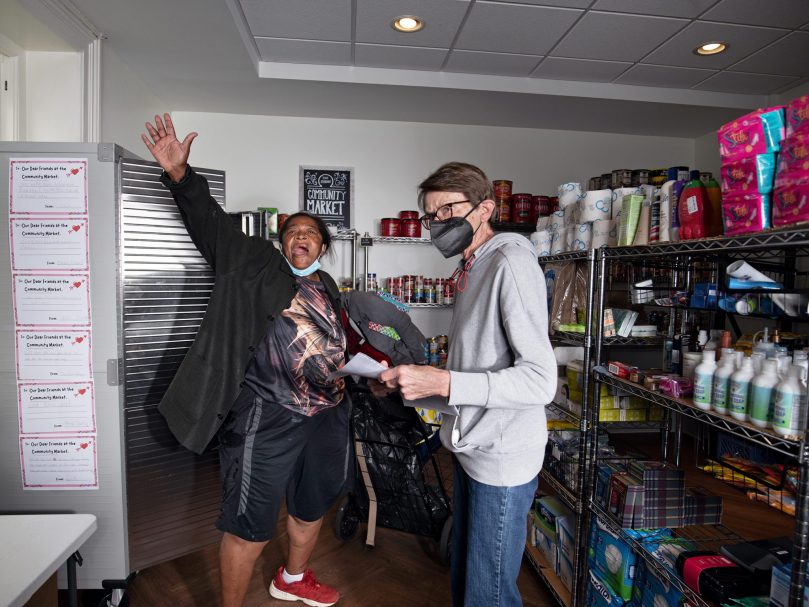 A Shrine Community Market visitor lets out a shout of praise while volunteer Esther Sutton assists her in shopping. Photo by Johnathon Kelso