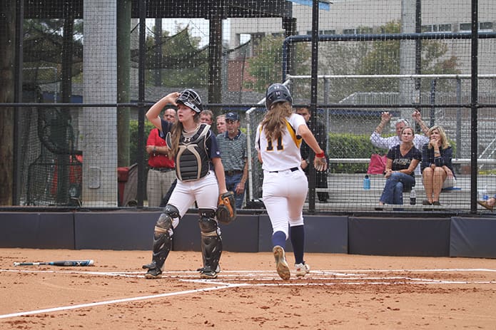 Pius catcher Morgan West looks to her teammates in the outfield during the first inning as Marist freshman Katie Goldberg approaches home plate to score the teamâs first run. Goldberg scored off of a double by Marist starting pitcher Kylie Burke. Photo By Michael Alexander