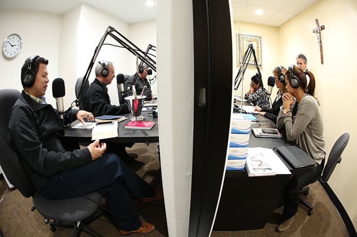 This angle provides a view of both sides of the studio. On the left are Father Jesús David Trujillo-Luna, foreground, pastor of St. Theresa Church, Douglasville, Bishop Luis R. Zarama and station volunteer German Medina of Our Lady of the Americas Mission. On the right are other station volunteers including Marisol Pérez, Marcela and Abel Galindo and Brenda Medina. Photo By Michael Alexander