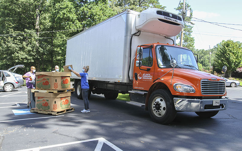 Karen Miller, right, pulls out a box of watermelon as the Atlanta Community Food Bank driver and a volunteer look on. Miller, a volunteer with St. Ann Church’s St. Vincent de Paul Society, coordinates the food pantry and the parish garden. Nearly 4,400 pounds of produce was brought to the Marietta parish July 13. Another 14,000 pounds of produce was delivered July 1. Photo By Michael Alexander