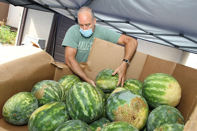 Andy Lover, a St. Vincent de Paul Society volunteer from St. Ann Church, unloads some of the watermelons delivered to St. Ann Church on July 13. Lover is also a member of the Adult Mission Ministry, which helped build Frederic’s Farm, the parish community garden. Photo By Michael Alexander