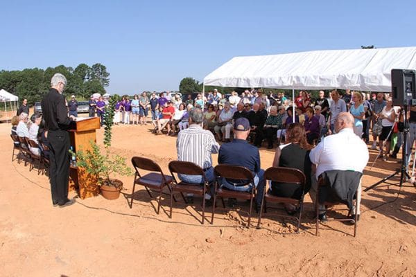 Father Daniel Toof, pastor of St. Anna Church, speaks to members of the congregation on the building site for the new church, parish hall and religious education classrooms. Photo By Michael Alexander