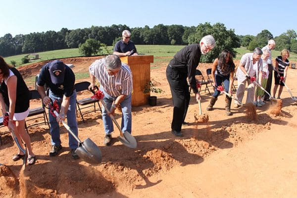 On the count of three (l-r) Betsy Jourdan, Jerry Hobbs, Ed Reinagel, Father Daniel Toof, Daniela Wieczorek, Vickie Chancey, Catherine and Dan Melton, and Carol Cernogorsky picked up a shovel full of dirt and turned it over, marking the climactic moment of the St. Anna Church groundbreaking, Sept. 7. Photo By Michael Alexander