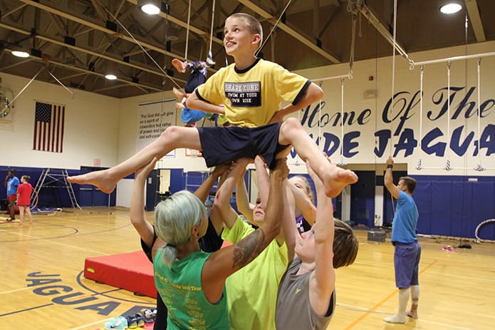 With the help of Circus of the Kids instructors and fellow students, Evan Hoekstra, top, a sixth-grader at St. Jude the Apostle School, Atlanta, reaches his full height while practicing the human balancing act on the first day of practice for the schoolâs upcoming circus. Photo By Michael Alexander