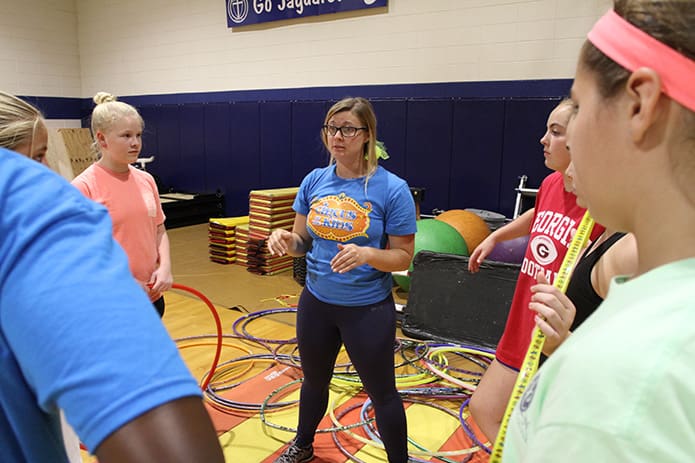 Hula-hoop instructor Taylor Byrnes, center, provides some insight about the act and how it should unfold as participants gather around her giving their undivided attention. Photo By Michael Alexander