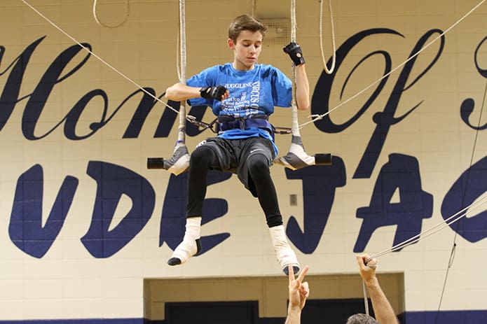 St. Jude seventh-grader Evan Sitzmann gets some instructions from Bruce Pheffer, standing below, as they prepare for the swinging trapeze act. Photo By Michael Alexander