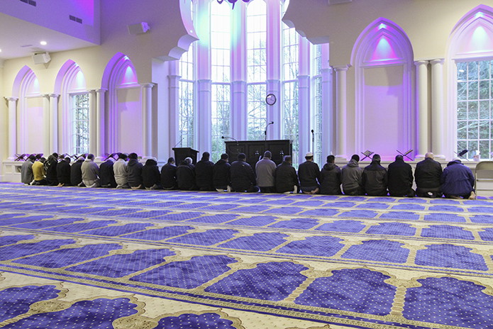 The men, barefoot or wearing only socks, go between standing and kneeling as they pray in the central heart of the Islamic Center of North Fulton in Alpharetta. Photo By Michael Alexander