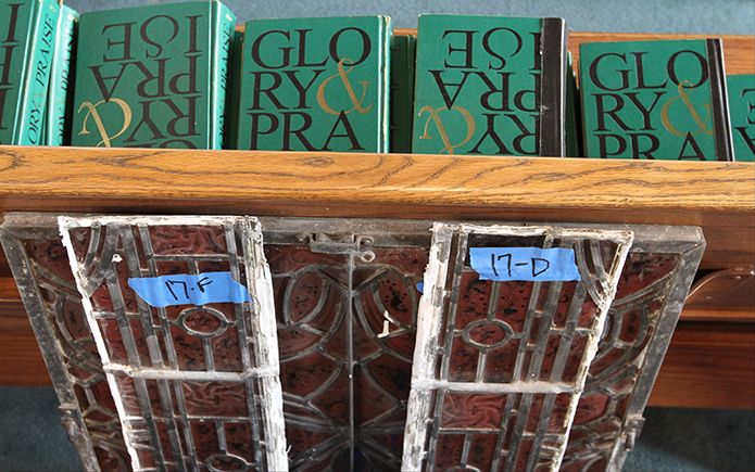 Like many others around the church, these stained glass window panels, labeled with their location, lean up against a pew inside the sanctuary before they are packed away. Photo By Michael Alexander