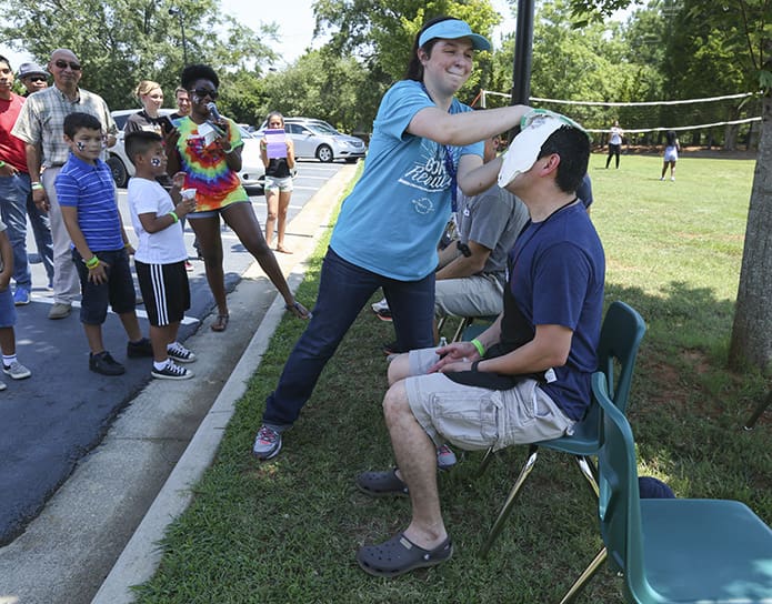 Rosemary York makes it a point to get her money's worth as she rubs the cream pie in the face and over the head of pastor Father Ignacio Morales