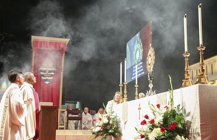 Deacon Dave Barron of Holy Family Church, Marietta, left, kneels with Archbishop Wilton D. Gregory during exposition of the Blessed Sacrament. Photo By Michael Alexander