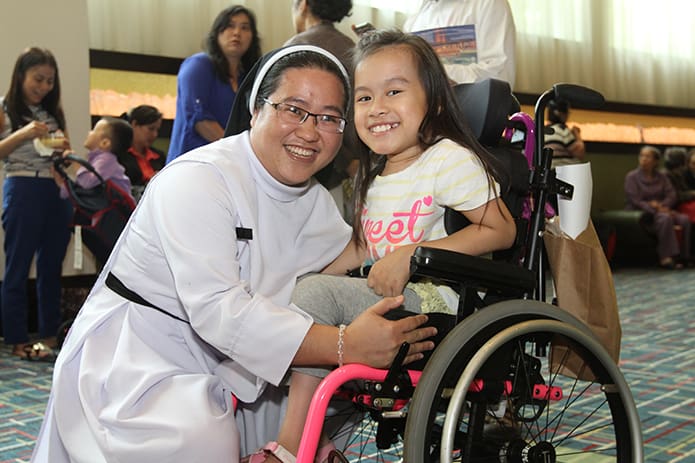 Sister Thuy-An Tran and 9-year-old Patricia Dang, both from the Holy Vietnamese Martyrs Church, Norcross, pose for a photo just outside the Vietnamese language track. Photo By Michael Alexander