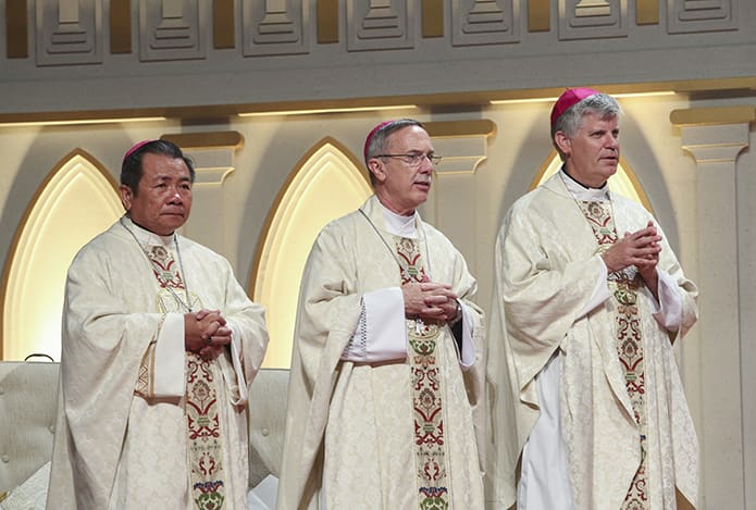 (L-r) Bishop Joseph Tri Ngoc Chau, the bishop of the Diocese of Lang Són-Cao Bang, Bishop Luis R. Zarama, and Bishop-designate Bernard E. (Ned) Shlesinger III stand at the altar during the closing liturgy’s Gospel reading. Photo By Michael Alexander