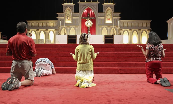 At the foot of the altar, some healing service attendees kneel before the Blessed Sacrament during a moment of praise and worship. It marked the opening evening of the 22nd annual Eucharistic Congress held June 16-17 at the Georgia International Convention Center in College Park. Photo By Michael Alexander