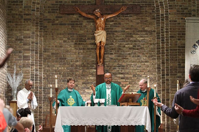 Father Michael Onyekuru, center, pastor of St. John the Evangelist Church, is joined on the altar by (l-r) Deacon Joseph Barker and Holy Cross Fathers Lou DelFra and Tim Scully, ACE Director of Spiritual Life and Director, Institute for Educational Initiatives, respectively. Photo By Michael Alexander