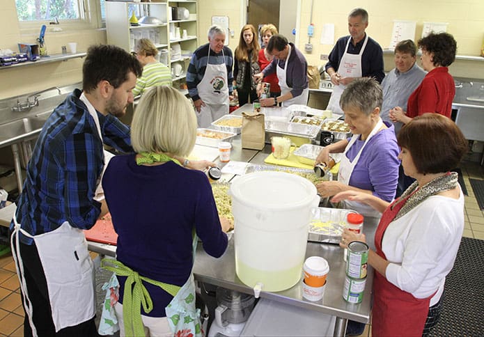 Volunteer members of the food preparation crew gather in the kitchen at the University of Georgia Catholic Center, Athens, hours before the 20th annual Thanksgiving dinner at the Jesse B. Denney Tower, a low-rise building for senior residents. They were making cornbread dressing, green bean casserole, and sweet potatoes, while turkeys cooked in the oven and potatoes and gravy cooked on top of the stove. Photo By Michael Alexander