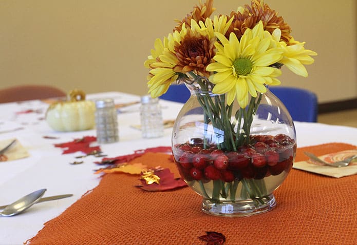 Emily Clutter decorated the tables with holiday trimmings and volunteers provided the place settings at the Jesse B. Denney Tower, Athens, in preparation of the Nov. 22 Thanksgiving dinner. Clutter, a senior at the University of Georgia, and her family volunteered in various capacities. Her mother Cathy coordinated the UGA Catholic Center Thanksgiving dinner for the third consecutive year. Photo By Michael Alexander