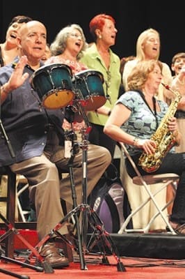 (Second from left, l-r) Bongo player Victor J. Alvarado, vocalists Joy Wittke, Denise Pizzini and Susan Critelli, and saxophonist Ginger Bisel join their fellow Transfiguration Church choir members in leading the opening hymn. Rod Voss is the music director for the Marietta choir.