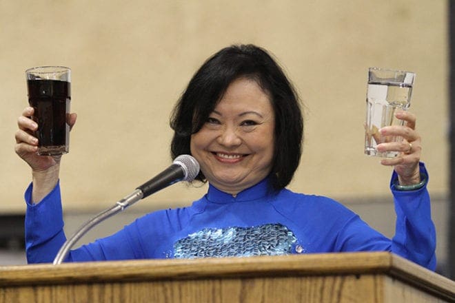 In her right hand Kim Phuc Phan Thi holds a glass of coffee, and in her left hand she holds a glass of water. Thi used the coffee to symbolize the darkness in her heart before she overcame the challenge to forgive, and the water represents her heart after she learned how to forgive those who had hurt her. She gave the example during an Oct. 22 presentation at Marist School’s Centennial Center. Photo By Michael Alexander