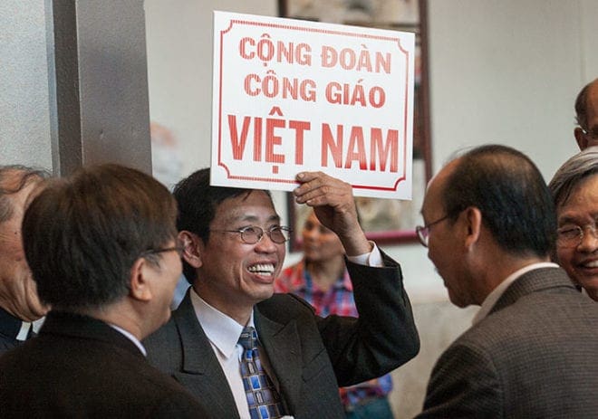 Dung Nguyen from Our Lady of Vietnam Church, Riverdale, holds up a sign to gather his fellow parishioners at the March 9 liturgy. Photo by Thomas Spink