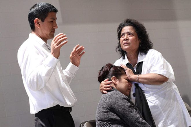 Juanita Martinez of St. Luke the Evangelist Church, Dahlonega, standing right, looks heavenward as she and Fidel Garcia of Good Shepherd Church, Cumming, left, pray with a woman. Martinez and Garcia were one of several prayer teams at the June 20 healing service. Photo By Michael Alexander