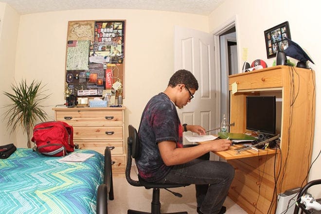 After arriving at the house from school, Sean McNeal grabs a quick bite to eat and he’s off to his room with a bottle of orange cream soda, where he works on his Latin homework. His room is filled with various video game posters, personal memorabilia and family photos. Photo By Michael Alexander