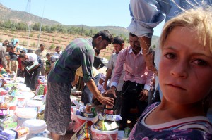 Members of the Yezidi religious minority who fled from violence in Mosul, Iraq, receive humanitarian aid Aug. 21 in Dohuk province, in the northern part of the country.  Catholic relief agencies are trying raise more money for additional aid in the region. CNS photo/EPA  