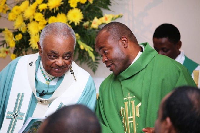 Archbishop Wilton D. Gregory, left, talks to Father JohnPaul Ezeonyido, right, the pastor of Christ Our Hope Church, at the parish's anniversary celebration Sept. 21. At the Mass to celebrate 30 years, Archbishop Gregory told parishioners, "You have endured infancy, adolescence, and now you are in your prime." Photo By Byron Henry