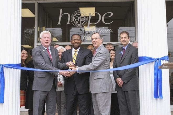 With members of the St. Vincent de Paul Georgia board of directors standing behind them, (l-r) John Berry, CEO and executive director of St. Vincent de Paul Georgia, Ceasar C. Mitchell, Atlanta City Council president, Jenner Wood, SunTrust Bank, Atlanta division president, and Kevin Barbee, chief operating officer of St. Vincent de Paul Georgia, prepare to cut the ceremonial ribbon at the entrance of its new Lakewood SunTrust Community Outreach Center, March 25.