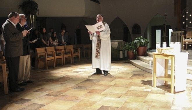 Joined by a standing congregation, Church of St. Ann associate pastor and La Salette Father John "Gabe" Gabriel leads the Mourner’s Kaddish in English. Photo By Michael Alexander